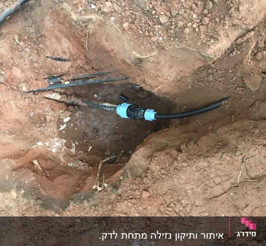 צינור שחור עם מחבר כחול באדמה חפורה
